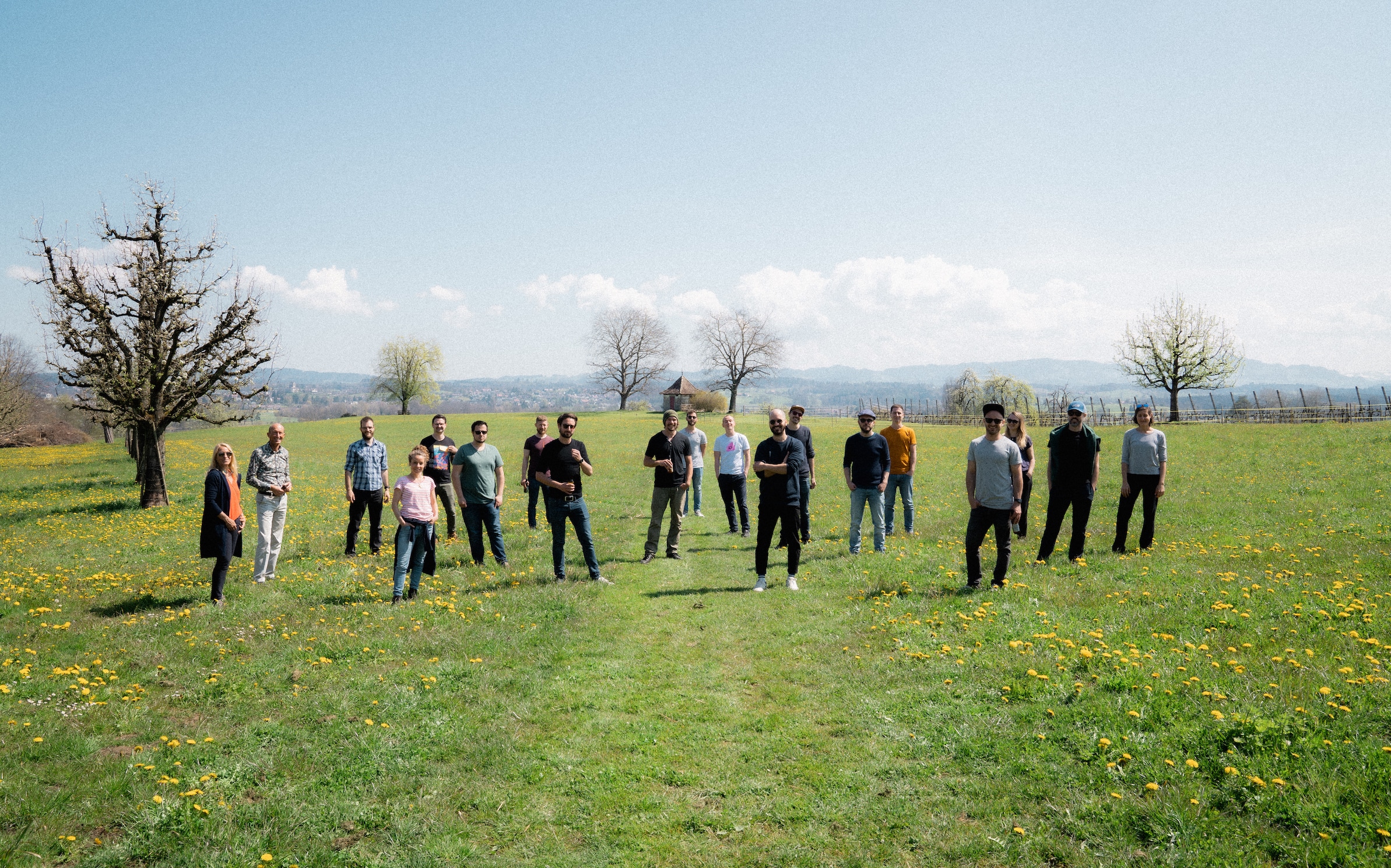 Ein Gruppenfoto von zwanzig Personen auf einer grossen Wiese.