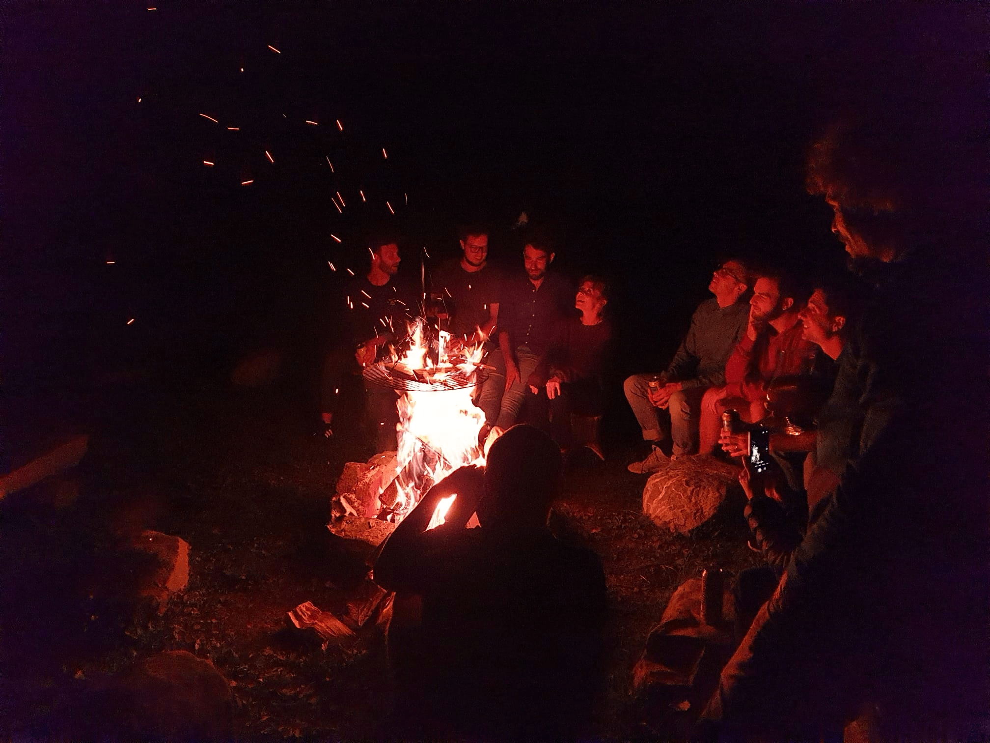 Eine Gruppe Menschen im dunkeln bei einem Lagerfeuer.