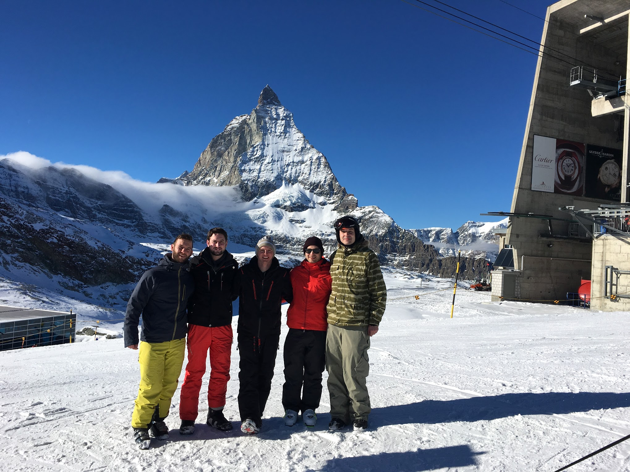 Fünf Personen in Skianzügen vor dem Matterhorn.